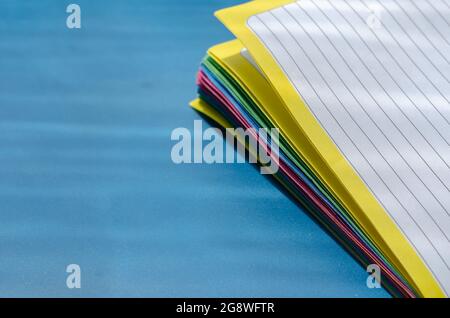 College-beherrschten Notizbuch, Nahaufnahme. Mehrfarbige Blätter Papier auf blau. Stockfoto