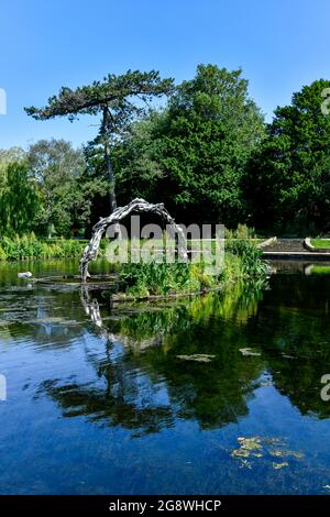 Die halbkreisförmige Continuum-Skulptur im Alexandra Park, Hastings. Die Reflexion im See vervollständigt das Kontinuum des Kreises. Stockfoto