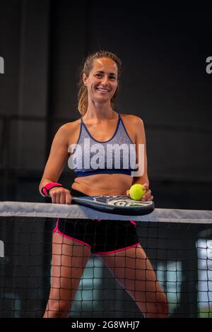 Porträt einer schönen Frau, die in der Halle einen Padel-Tennisplatz spielt Stockfoto