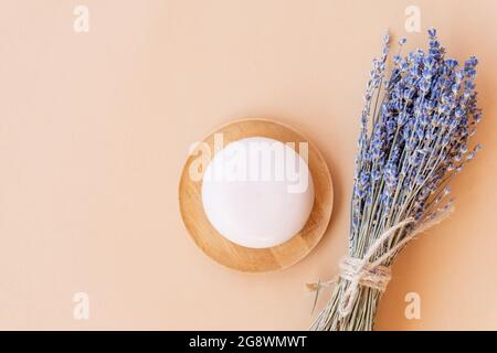 Handgemachte Lavendelseife. Stück natürliche Seife in Kugelform mit getrockneten Lavendelblüten auf einem Holzteller. Bio-Kosmetik für Hautpflege und Spa. Stockfoto