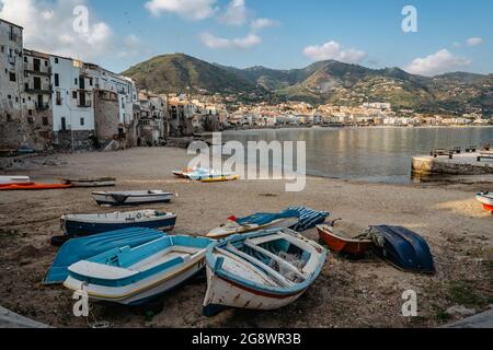 Schöner alter Hafen mit hölzernen Fischerbooten, bunten Steinhäusern am Wasser und Sandstrand in Cefalu, Sizilien, Italien. Attraktive Sommer-Stadtlandschaft, t Stockfoto