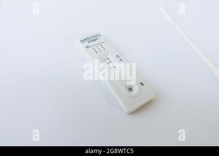 Covid-19 Schnelltest-Kit, Antigentest, Hometest neben dem Tupfer mit positivem (zwei Linien) Ergebnis. Stockfoto