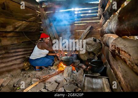 Eine Frau, die in der Dorfhütte in Kibale, Uganda, das Feuer anzündet Stockfoto