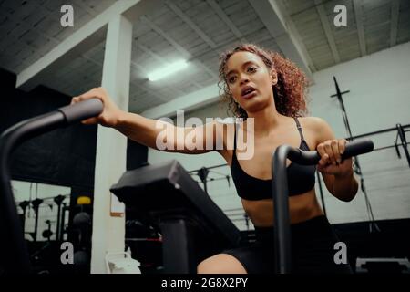 Afroamerikanische Frau, die während des Crosstrainings einen Crosstrainer verwendet. Weibliche Sportlerin beim Training im Fitnessstudio. Hochwertige Fotos Stockfoto