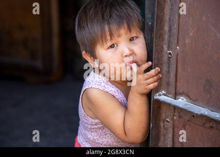 Kirgisisches Mädchen, das ihren Daumen saugt und posiert, Bischkek, Kirgisistan Stockfoto