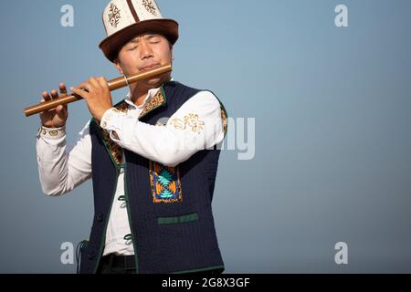 Kirgisischer Musiker, der in Issyk Kul, Kirgisistan, ein traditionelles seitliches Musikinstrument namens Sybyzgy spielt Stockfoto