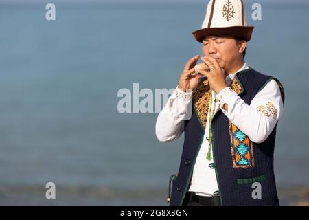 Kirgisischer Musiker, der in Issyk Kul, Kirgisistan, traditionelles lokales Instrument spielt. Stockfoto