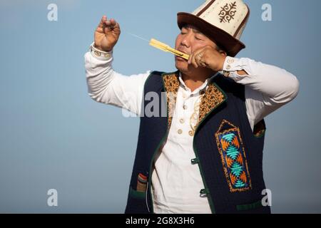 Kirgisischer Musiker, der in Issyk Kul, Kirgisistan, traditionelles lokales Instrument spielt. Stockfoto