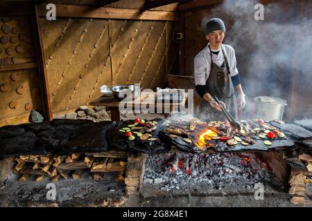 Der kirgisische Koch grillt Fleisch auf traditionelle Weise auf der Steinplatte in Bischkek, Kirgisistan Stockfoto