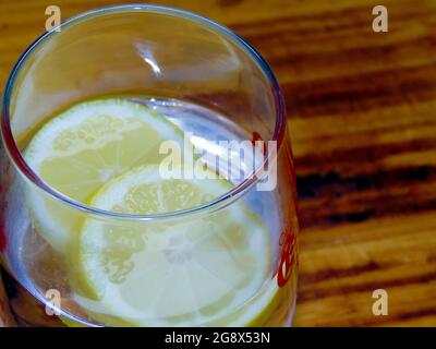 Abschluss einer erfrischenden Tasse Limonade mit Zitrone und Eis auf einer dunklen Holzoberfläche Stockfoto