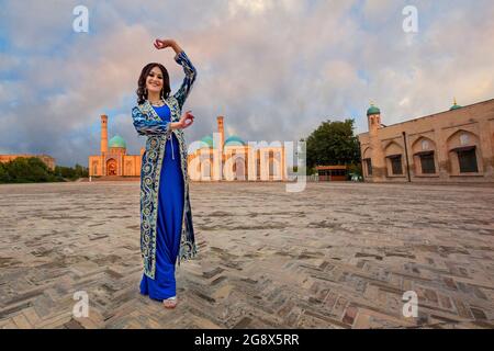 Usbekische Frau in lokaler Kleidung mit Khast Imam Moschee im Hintergrund in Taschkent, Usbekistan Stockfoto