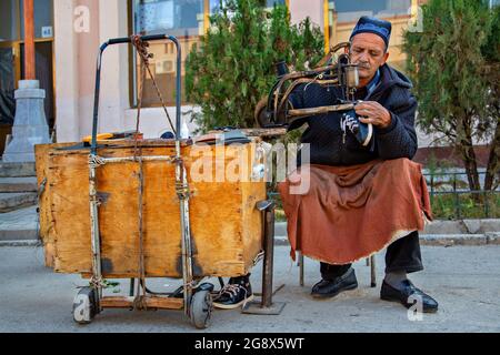 Usbekischer Mann repariert Schuhe an seinem tragbaren Stand in Samarkand, Usbekistan Stockfoto