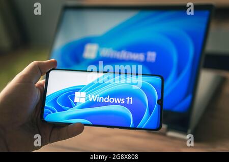 23. Juni 2021. Barnaul, Russland. Mann mit einem Laptop und einem Smartphone, Windows 11 neues Microsoft-Betriebssystem auf den Bildschirmen Stockfoto