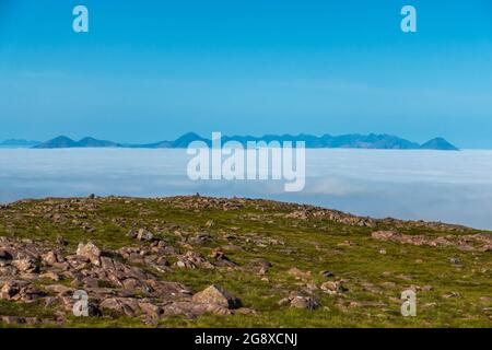 Eine Wolkeninversion der fernen Cuillin Ridge Berge auf der Insel Skye, Schottland, vom Gipfel des Bealach Na Ba bei Applecross aus gesehen Stockfoto