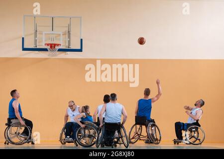 Behinderte Kriegsveteranen gemischten Rennen gegen Basketball-Teams in Rollstühlen fotografiert in Aktion, während ein wichtiges Spiel in einer modernen Halle spielen. Stockfoto