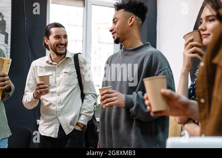 Eine Gruppe von Studenten, die während einer Kaffeepause im Haus sprechen Stockfoto