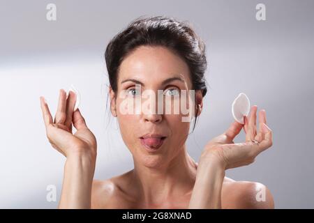 Eine Frau, die Spaß mit einem Paar Wattepads hat. Ihre Zunge herausstreckt. Stockfoto