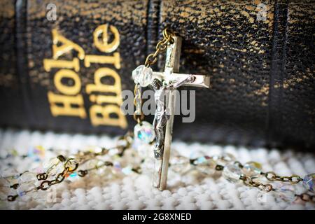 Ein Rosenkranz wird gegen eine alte verwitterte bibel aufgestobt. Stockfoto