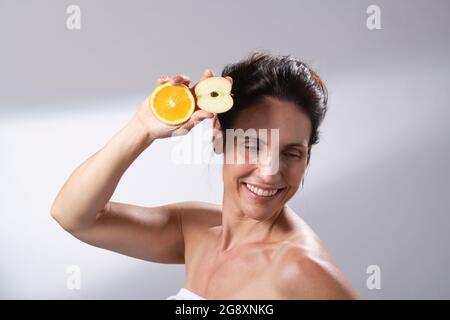 Eine Frau, die frisches Obst in den Händen hält. Einen halben Apfel und eine halbe Orange. Stockfoto