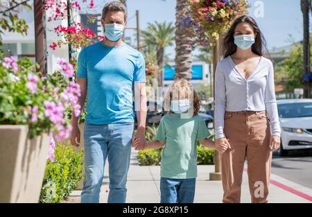 Familie während der Coronavirus-Pandemie. Eltern mit Kind Junge tragen medizinische Maske. Stockfoto