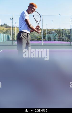 Der junge Mann schoss aus tiefem Winkel und wartete auf den Tennisball Stockfoto