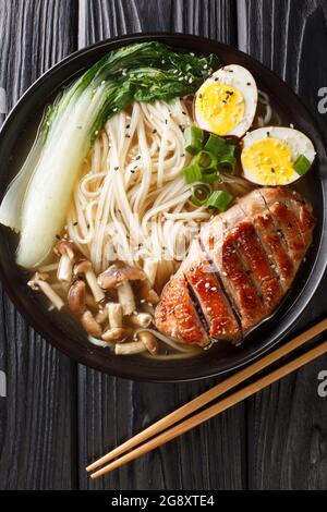 Ramen mit Ente, Pilzen, Eiern und Bok Choy in einer Schüssel auf dem Tisch. Vertikale Draufsicht von oben Stockfoto