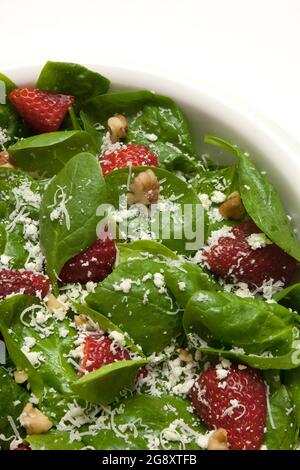 Ein gesunder, frischer Spinatsalat mit Streubeeren, Feta-Käse, Walnüssen und einem harten Parmesan im romano-Stil Stockfoto