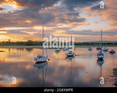 An einem Sommerabend vertäuten Yachten im Hafen von Chichester. Sonnenuntergangslicht und stilles Wasser sorgen für Farbe und Reflexionen. Stockfoto