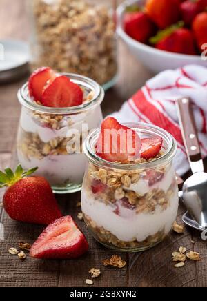 Granola Parfait mit Erdbeerjoghurt und frischen Erdbeeren auf einem Holztisch Stockfoto