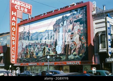 Harold's Club, ein Casino in der North Virginia Street, Reno, Nevada, USA, wurde Mitte der 1950er Jahre angesehen. Der Verein wurde 1935 gegründet. Vor dem Casino wurde ein großes 70 x 35 Meter großes Wandgemälde mit alten Pioniersiedlern aus dem Westen, das einen Wagenzug und Indianer zeigt, ausgestellt. Das Wandbild wurde 1949 von Theodore McFallon entworfen und seine handbemalten Keramikfliesen wurden von Sargent Claude Johnson angefertigt. Über dem Wandgemälde stand ‘in aller Demut denen gewidmet, die den Weg loderten’. Das Gebäude wurde 1999 abgerissen. Das Wandgemälde wurde 2007 im Reno Livestock Events Center ausgestellt. Stockfoto