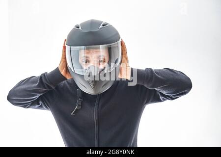 Mann mit Motorradhelm, der Daumen nach oben gedeutet hat. Isoliert auf weißer Studiowand. Stockfoto