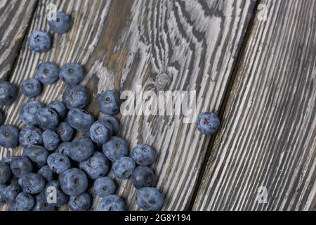 Heidelbeeren sind auf Kiefernbrettern verstreut. Nahaufnahme. Stockfoto