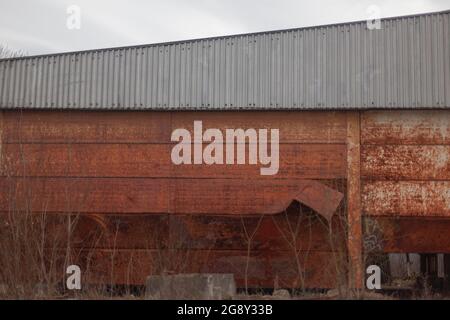 Verlassene Lagergebäude. Eine rostige Wand an einem großen Haus. Das Lager war lange Zeit leer. Verlassene Immobilien. Stockfoto