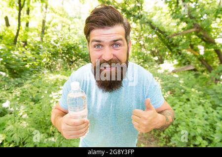 Guy hält den Körper Wasserhaushalt. Hydratation. Täglich Wasser. Fröhlich bärtigen Mann halten Flasche Stockfoto