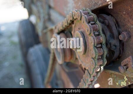 Rostige Details von alten verlassenen Autos. Zahnräder, Ketten, Riemenscheiben rosten im offenen Bereich. Moosbedeckte Metallteile von Landmaschinen. Stockfoto