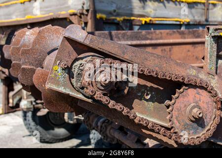 Rostige Details von alten verlassenen Autos. Zahnräder, Ketten, Riemenscheiben rosten im offenen Bereich. Moosbedeckte Metallteile von Landmaschinen. Stockfoto