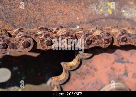 Rostige Details von alten verlassenen Autos. Zahnräder, Ketten, Riemenscheiben rosten im offenen Bereich. Moosbedeckte Metallteile von Landmaschinen. Stockfoto