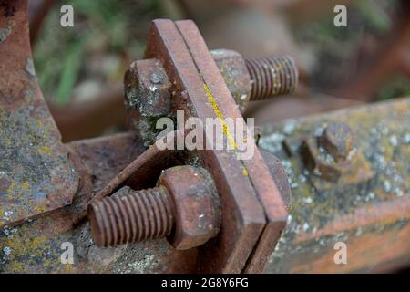 Rostige Details von alten verlassenen Autos. Zahnräder, Ketten, Riemenscheiben rosten im offenen Bereich. Moosbedeckte Metallteile von Landmaschinen. Stockfoto