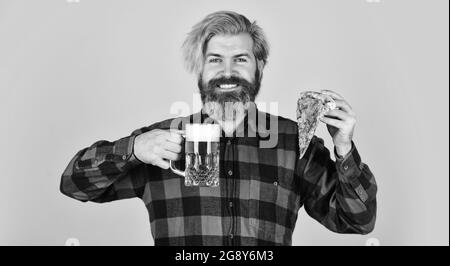 Glücklicher bärtiger Mann mit Bier und Pizza. italienisches Essen. italien ist hier. Kerl in der Bar Bier trinken und Pizza essen. Prost. Glas Bier und Pizza Stockfoto