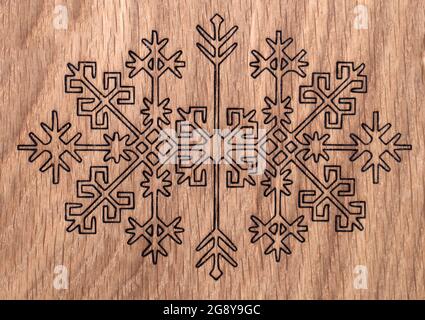 Lettische antike Ornamente in Holz verbrannt; auf Holzplatte abgebildet Stockfoto