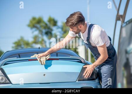 Mann in Overalls gründlich wischen Auto Stockfoto