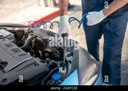 Mann Hände mit Gerät in offener Haube des Autos Stockfoto