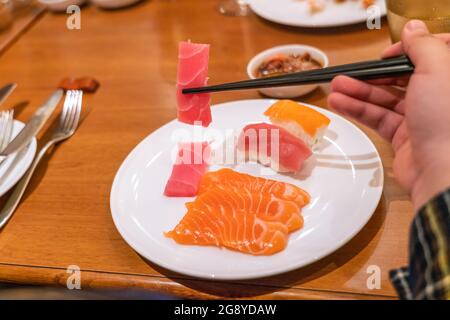 Frau, die Sashimi mit Essstäbchen isst Stockfoto