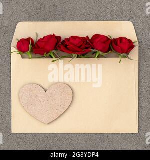 Strauß roter Rosen in einem Umschlag mit Herz. Postkarte mit Platz für Design. Stockfoto