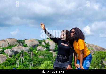 Nahaufnahme zweier junger afrikanischer Weibchen, die unter Sonnenlicht Selfies im Freien machen Stockfoto