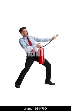 Löschen des Feuers. Porträt eines jungen kaukasischen Mannes, Büroangestellter mit Feuerlöscher isoliert auf weißem Hintergrund. Stockfoto