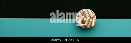 Niacin-Kapseln auf blauem und schwarzem Hintergrund. Nahrungsergänzungsmittel Draufsicht Banner. Geistiges Wohlbefinden und persönliches Gesundheitskonzept Stockfoto