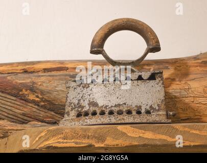 Nahaufnahme von antikem Glätteisen auf dekorativem Holz. Stockfoto