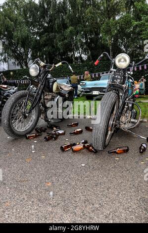 Bei der Neugestaltung eines Motorradtreffen beim Goodwood Revival, Großbritannien, wurden Bierflaschen um amerikanische Oldtimer-Motorräder herumgestreut. Szene aus der Zeit der USA Stockfoto