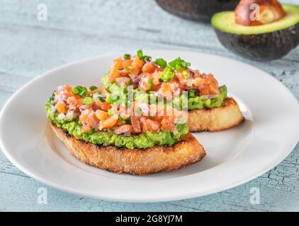Zwei Guacamole und Lachs Toasts auf weißem Teller Stockfoto